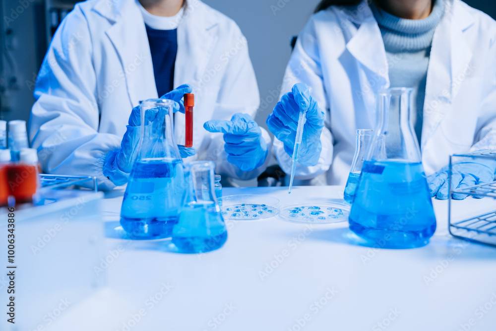 Two Scientist mixing chemical liquids in the chemistry lab. Researcher working in the chemical laboratory Two Scientist mixing chemical liquids in the chemistry lab. Researcher working in the chemical laboratory