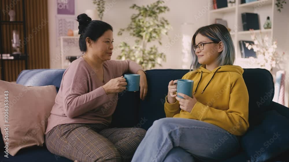 Teenage girl and mom talking and drinking tea on couch, trusting relationship Teenage girl and mom talking and drinking tea on couch, trusting relationship