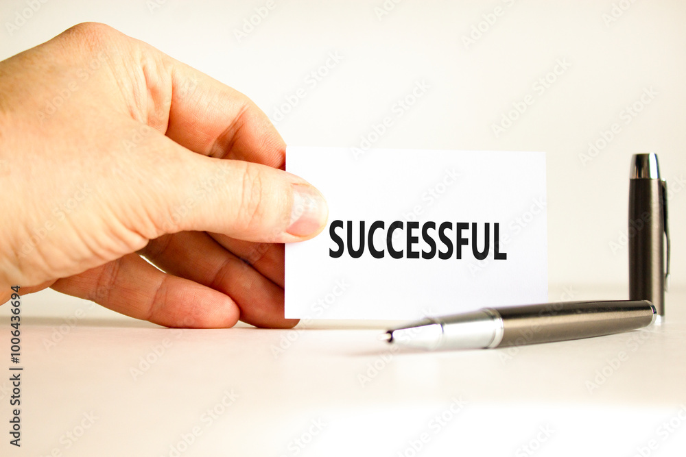 Successful symbol. Concept word Successful on beautiful white card. Beautiful wooden background. Businessman hand. Beautiful black pen. Business successful concept. Copy space. Successful symbol. Concept word Successful on beautiful white card. Beautiful wooden background. Businessman hand. Beautiful black pen. Business successful concept. Copy space.