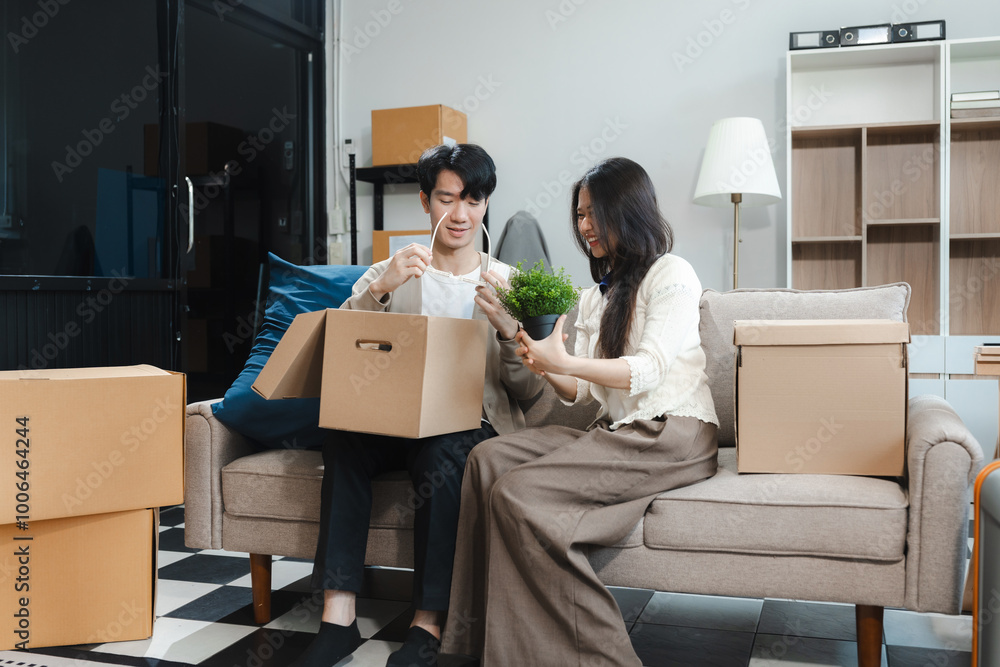 Young couple relaxing sitting on the sofa using the computer laptop around cardboard boxes, very happy moving to a new house. Young couple relaxing sitting on the sofa using the computer laptop around cardboard boxes, very happy moving to a new house.
