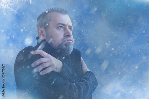 Frozen man shivering from cold weather on a blue snowy background. Winter cold concept