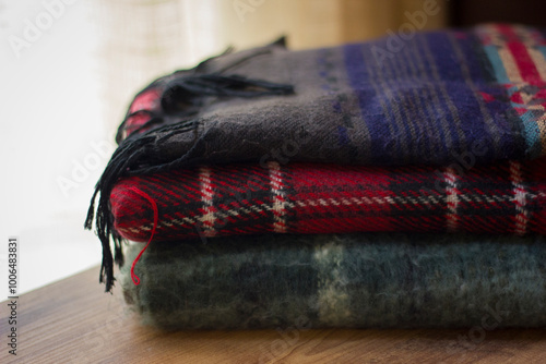 Stack of folded knitted wool scarf, Season of warm knitwear red, green, wood.