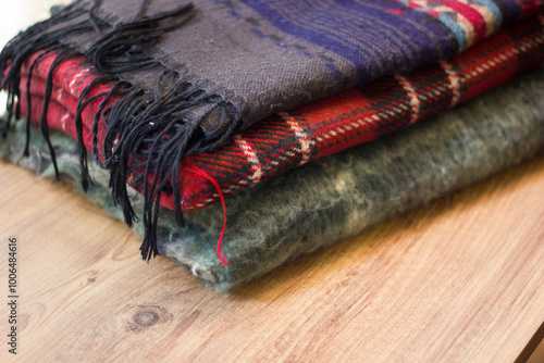 Stack of folded knitted wool scarf, Season of warm knitwear red, green, wood.