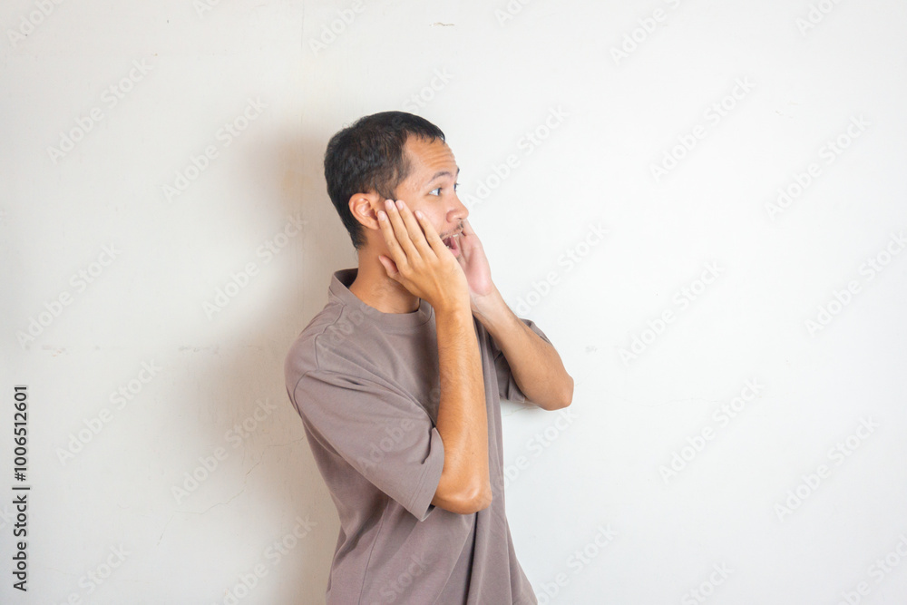 Shocked young asian men with hands on cheeks Shocked young asian men with hands on cheeks