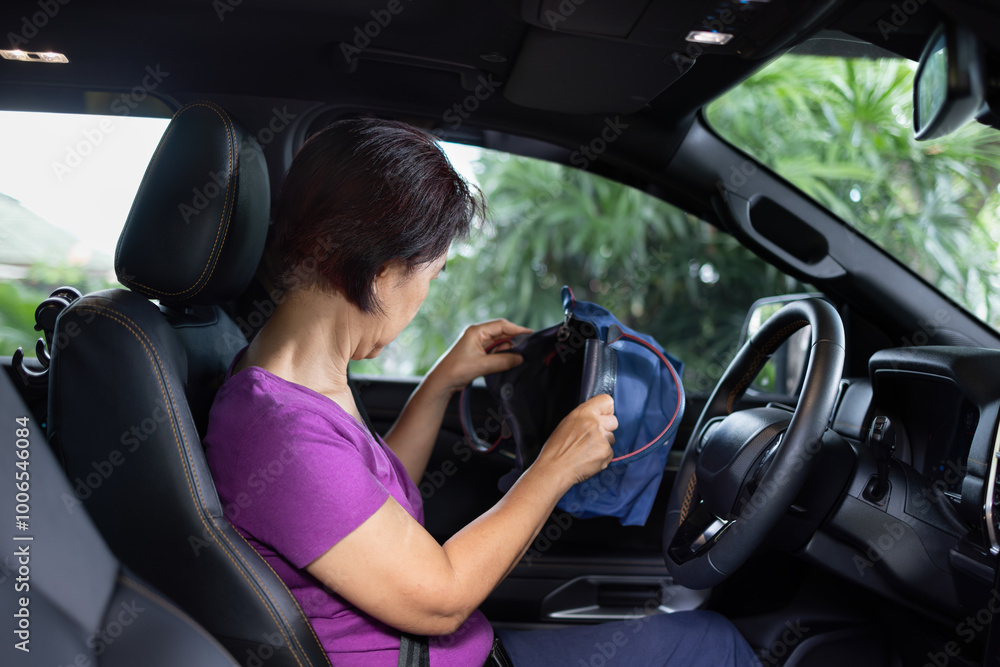 Senior asian woman sitting on drivers seat and look for a key inside handbag. Senior asian woman sitting on drivers seat and look for a key inside handbag.