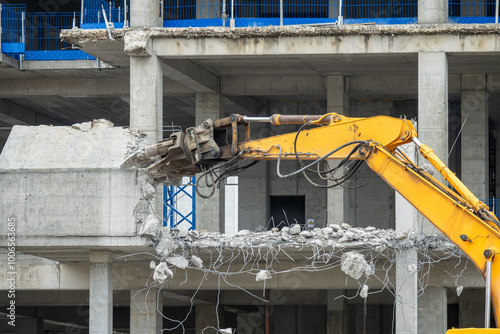 Excavator machine with hydraulic crashers at demolition of the house. House being demolished by special machinery. photo