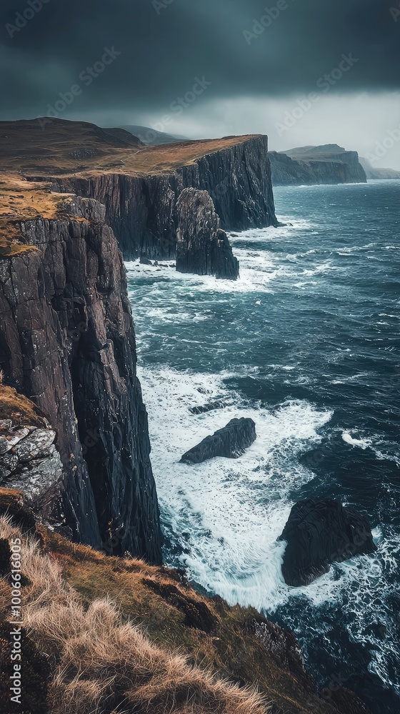 Naklejka premium A rugged cliffside meets turbulent ocean waves under a moody sky, creating a dramatic coastal landscape filled with natural beauty.