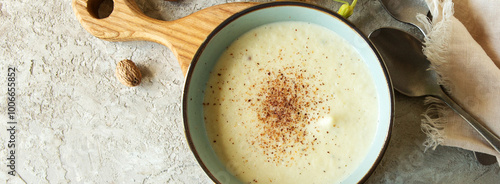 bowl of celery root soup with nutmeg on a table, top view

