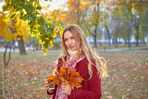 A woman in a red coat and a black skirt walks in an autumn park. The concept of autumn and the beauty of nature.