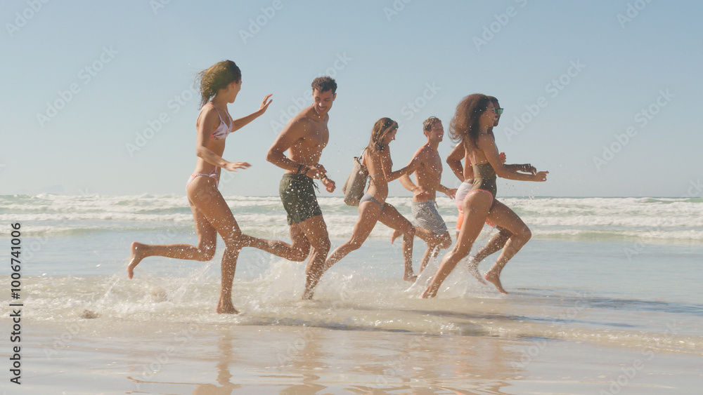 Φωτογραφία Group Of Friends In Swimwear Run Through Waves Together On Summer Beach Vacation