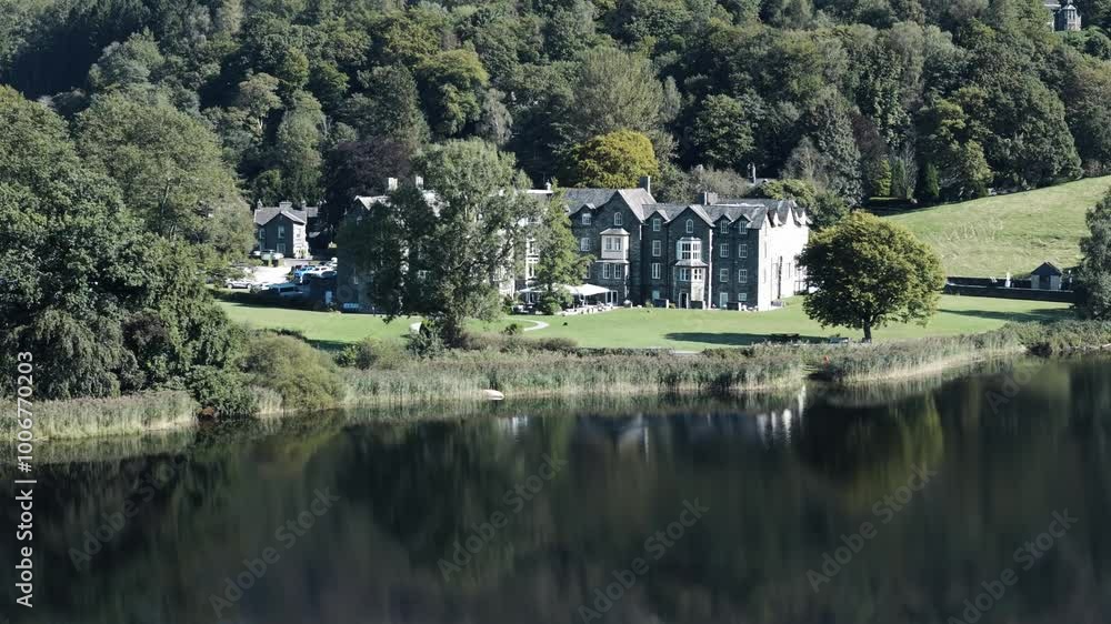 Aerial establishing orbit of Grassmere Lake and lakeside hotel with reflection of building and trees shimmering in water Aerial establishing orbit of Grassmere Lake and lakeside hotel with reflection of building and trees shimmering in water