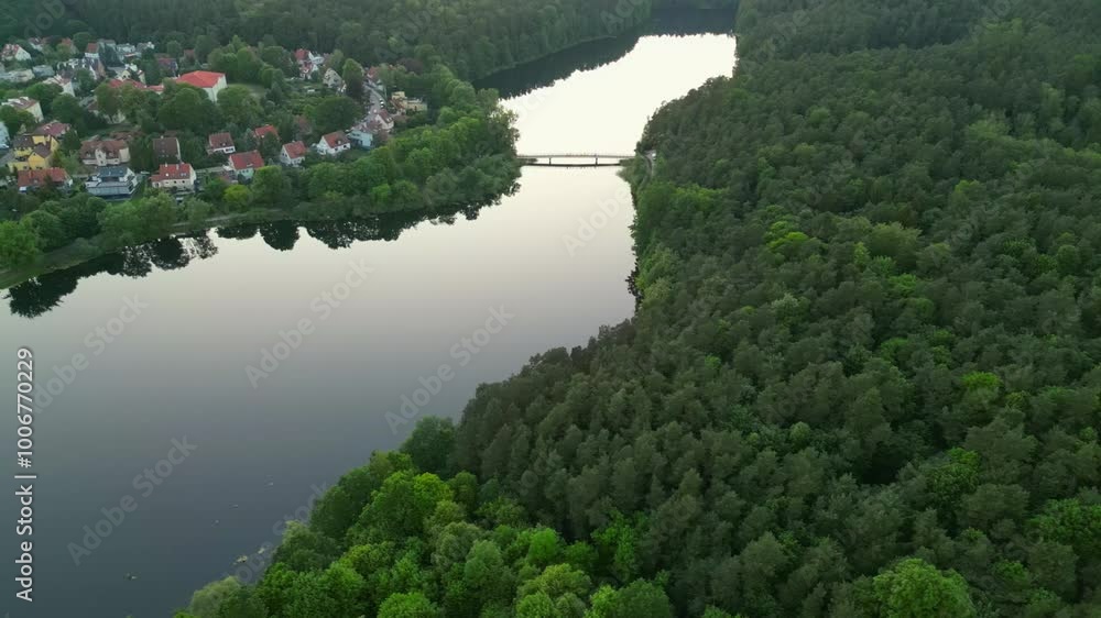Evening drone flight. View of a long lake with reflections of trees on the water's surface Evening drone flight. View of a long lake with reflections of trees on the water's surface