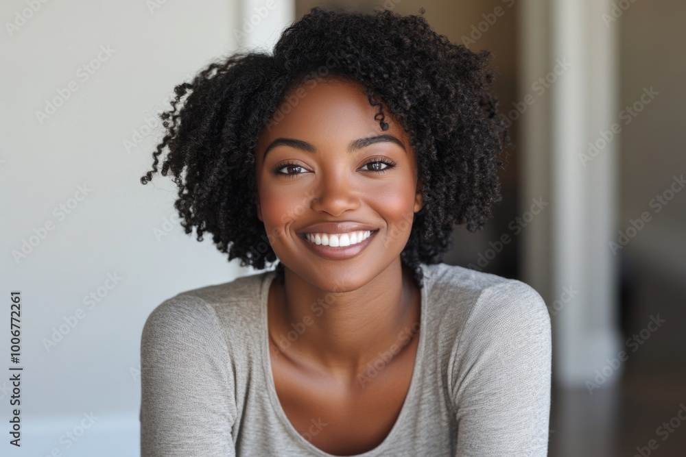 Fototapeta premium a black woman, smiling and looking at the camera in her living room. 
