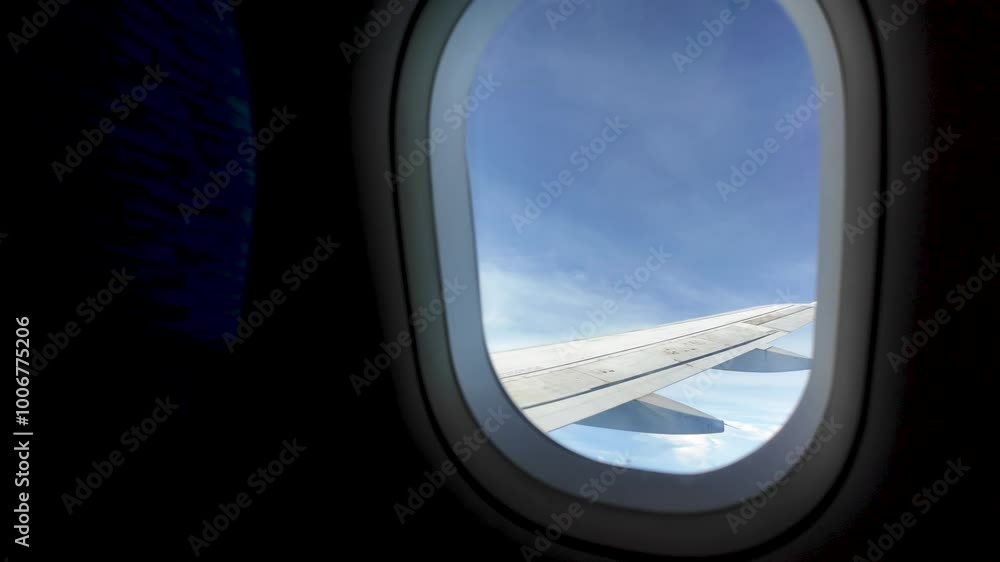 View of an airplane wing soaring through a blue sky with white clouds, as seen from the passenger window View of an airplane wing soaring through a blue sky with white clouds, as seen from the passenger window