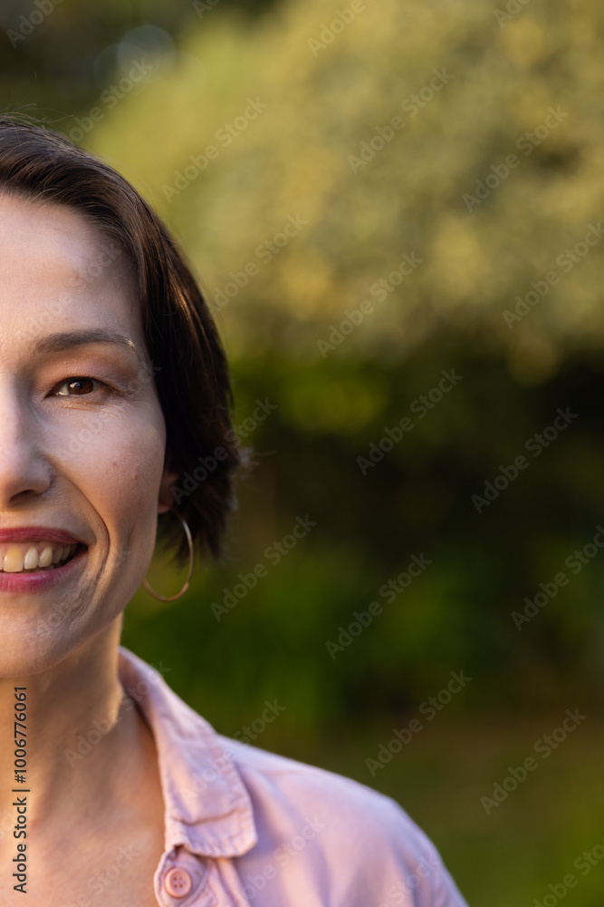 Smiling middle-aged woman with short hair wearing pink shirt and hoop earring outdoors, copy space Smiling middle-aged woman with short hair wearing pink shirt and hoop earring outdoors, copy space