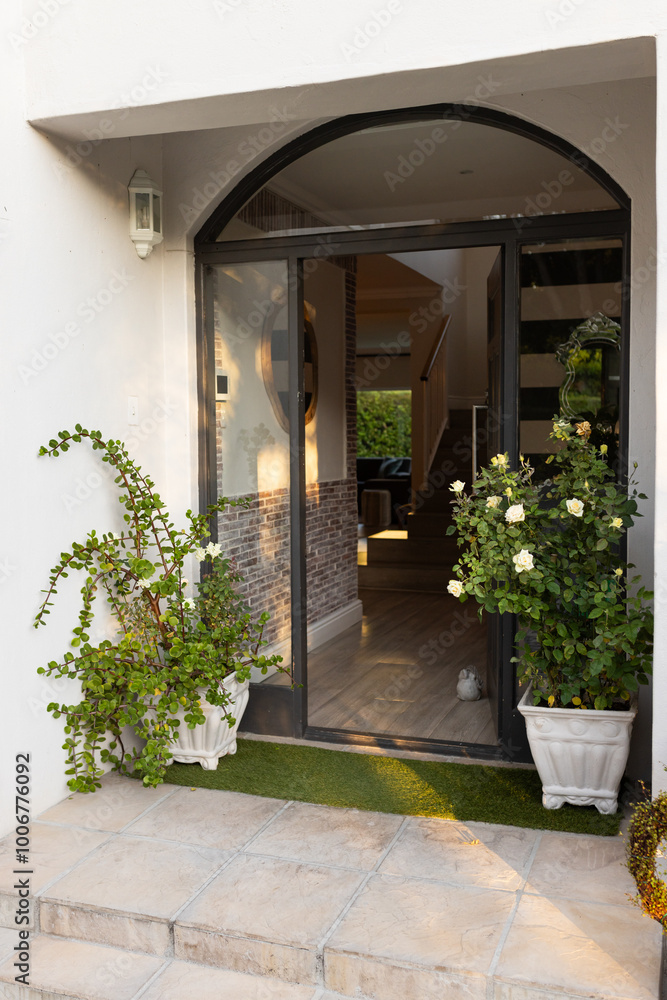 Fototapeta premium Outdoors, Open front door of modern home with potted plants and inviting entryway