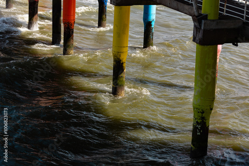 Wallpaper Mural Colored and weathered pillars of a pier. Waves breaking between the pillars. Calm North Sea, shallow waves and calm sea. Sunny day, beach in The Hague, Netherlands. Torontodigital.ca