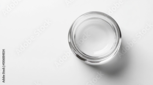 Close-up of moisturizer in a clear jar, top view, glossy finish. Smooth surface with no branding. Simple, minimalist white background.