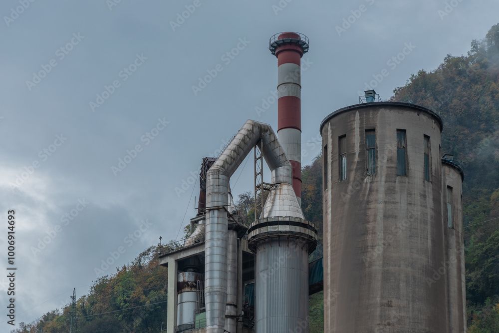 View of cement factory in Trbovlje, Slovenia. Visible chimneys and towers on a cloudy rainy day. Polluiting the valleys of Zasavje.