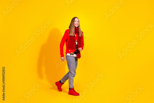 Full body portrait of nice young girl walk empty space wear festive new year sweater isolated on yellow color background