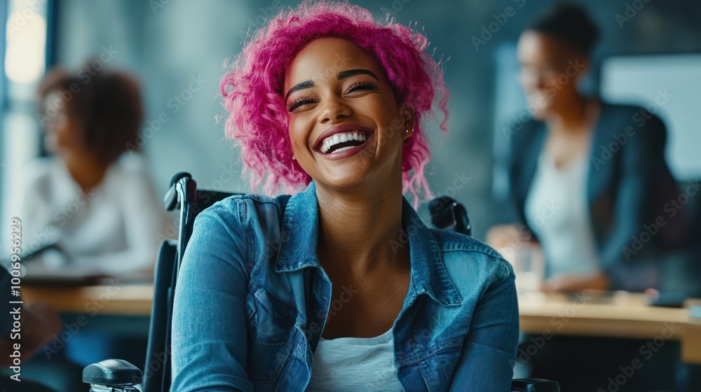 Fototapeta premium Inclusive image of a happy mixed race lesbian employee sitting in a wheelchair laughing with colleagues in a team meeting. Disabled black working woman with pink hair. Inclusion & diversity workplace