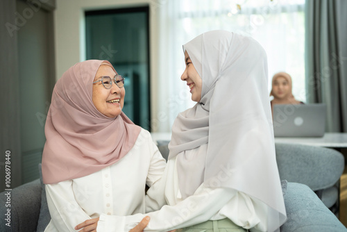 Happy muslim mother and daughter smiling to each other in a living room