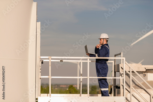 engineers working and holding the report at wind turbine farm Power Generator Station on mountain,Thailand people,Technician man and woman discuss about work