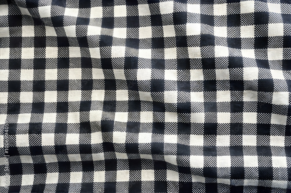 A black and white checkered fabric lies smoothly over a surface, its soft folds creating an inviting texture and visual interest in the material. Generative AI A black and white checkered fabric lies smoothly over a surface, its soft folds creating an inviting texture and visual interest in the material. Generative AI