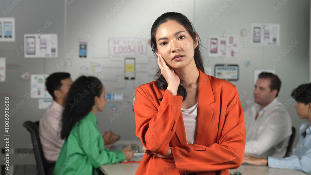 Fototapeta premium Asian professional businesswoman standing with confident at creative business meeting. Beautiful confident leader posing while diverse business people discussion about using Ux and Ui design