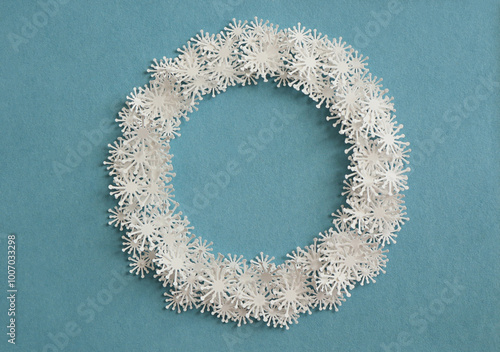 A circle of paper snowflakes on a blue background.. Christmas wreath made of paper snowflakes. Christmas background cut out from paper. photo