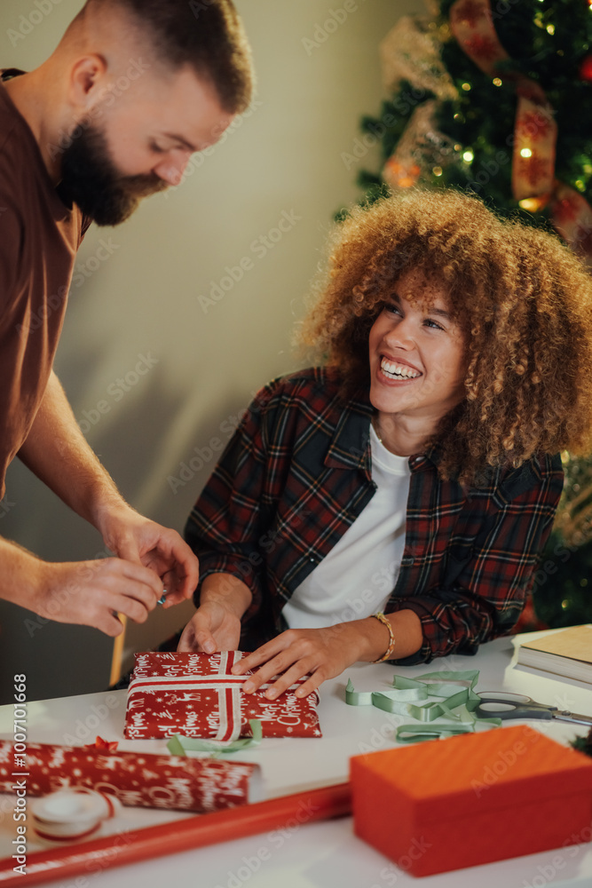 Fototapeta premium Happy couple wrapping christmas gifts together at home