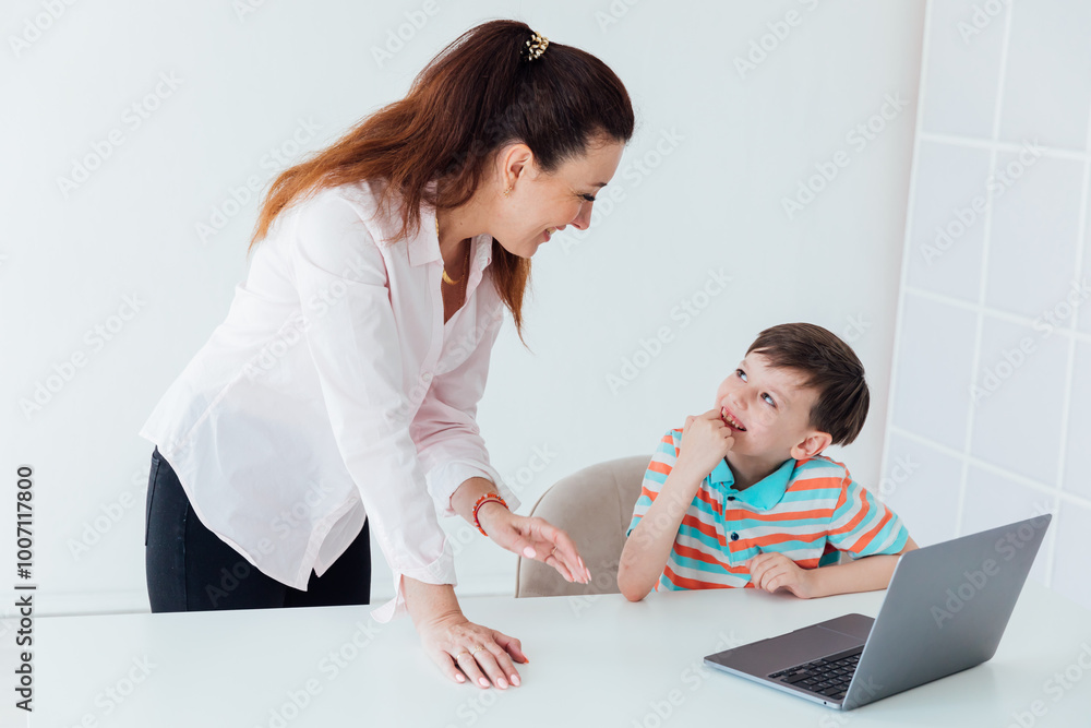 Female teacher teaching schoolboy on laptop at desk Female teacher teaching schoolboy on laptop at desk