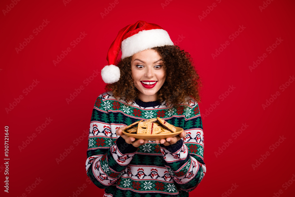 Portrait of nice young girl look cookies plate wear new year xmas sweater isolated on red color background Portrait of nice young girl look cookies plate wear new year xmas sweater isolated on red color background