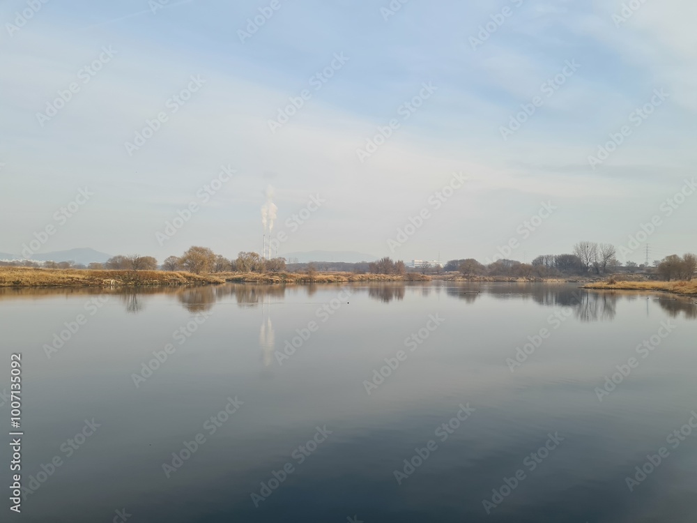 Fototapeta premium Tranquil river landscape with reflections on still water