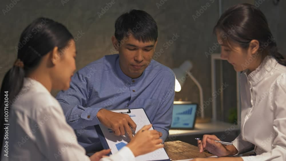 Manager holds a chart while explaining growth to colleagues during a meeting in a corporate office setting Manager holds a chart while explaining growth to colleagues during a meeting in a corporate office setting