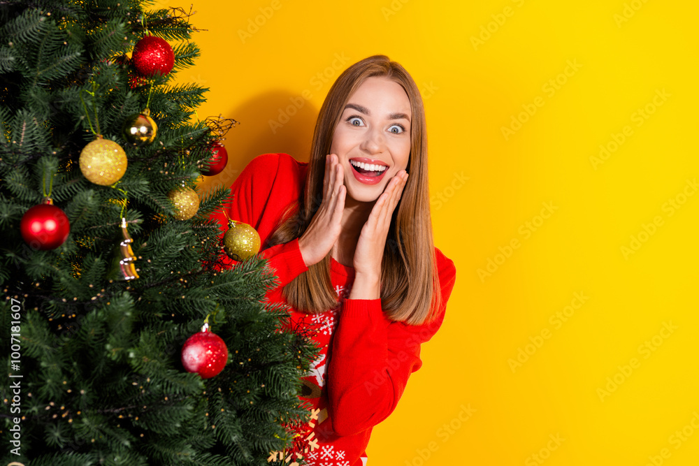 Portrait of nice young girl behind tree empty space wear festive new year sweater isolated on yellow color background Portrait of nice young girl behind tree empty space wear festive new year sweater isolated on yellow color background