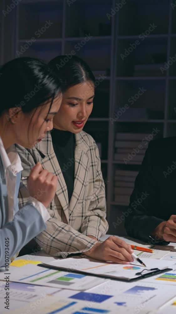 Businesswomen working late in the office, analyzing financial data and strategizing for future growth and success Businesswomen working late in the office, analyzing financial data and strategizing for future growth and success