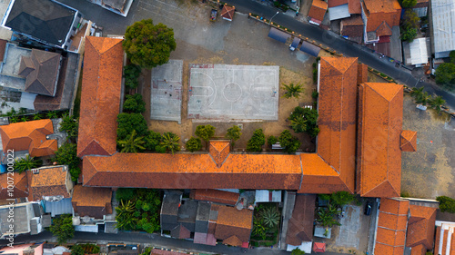 Captivating aerial view showcasing the intricate terracotta rooftops of a school complex, harmoniously integrated within a bustling residential areab