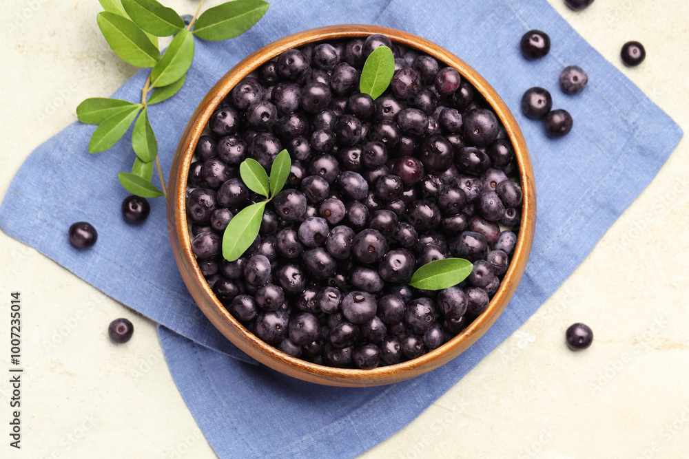 Ripe acai berries and leaves in bowl on light table, flat lay Ripe acai berries and leaves in bowl on light table, flat lay