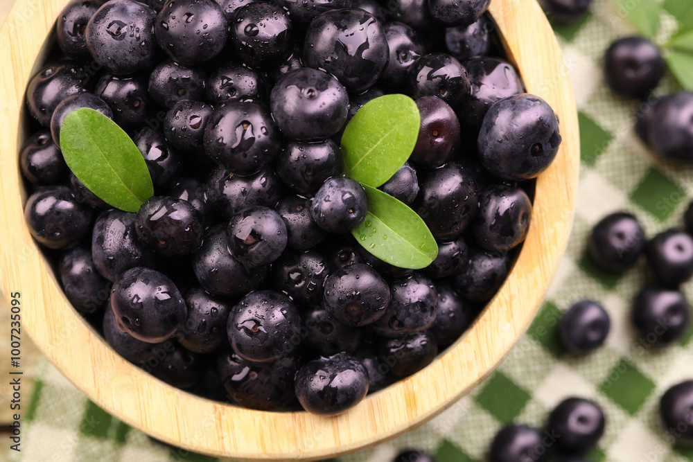 Ripe acai berries and leaves in bowl on table, top view Ripe acai berries and leaves in bowl on table, top view