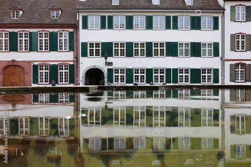 Häuser auf dem Münsterplatz in Basel spiegeln sich in einem Brunnen photo