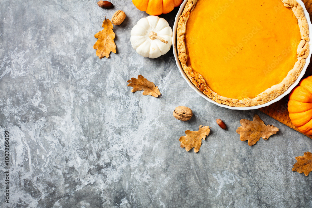 Homemade pumpkin pie with autumn leaves and nuts on gray background. Perfect for fall recipes, Thanksgiving, and holiday baking themes Homemade pumpkin pie with autumn leaves and nuts on gray background. Perfect for fall recipes, Thanksgiving, and holiday baking themes