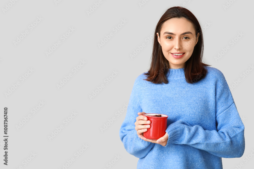 Happy young woman with cup of hot mulled wine on grey background Happy young woman with cup of hot mulled wine on grey background