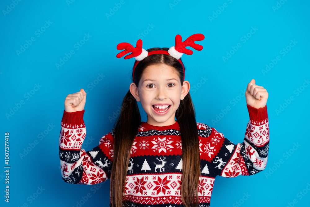 Photo of cheerful positive girl wear red sweater christmas festive event hand fist isolated on blue color background Photo of cheerful positive girl wear red sweater christmas festive event hand fist isolated on blue color background