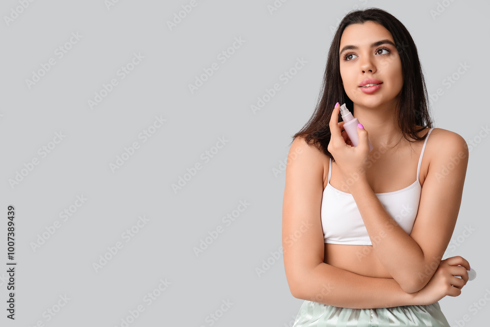 Beautiful young woman holding bottle of cosmetic product on grey background Beautiful young woman holding bottle of cosmetic product on grey background