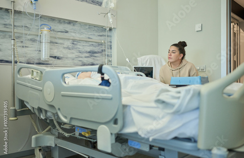 Young woman cares for and accompanies her elderly grandmother lying in bed in her hospital room after surgery