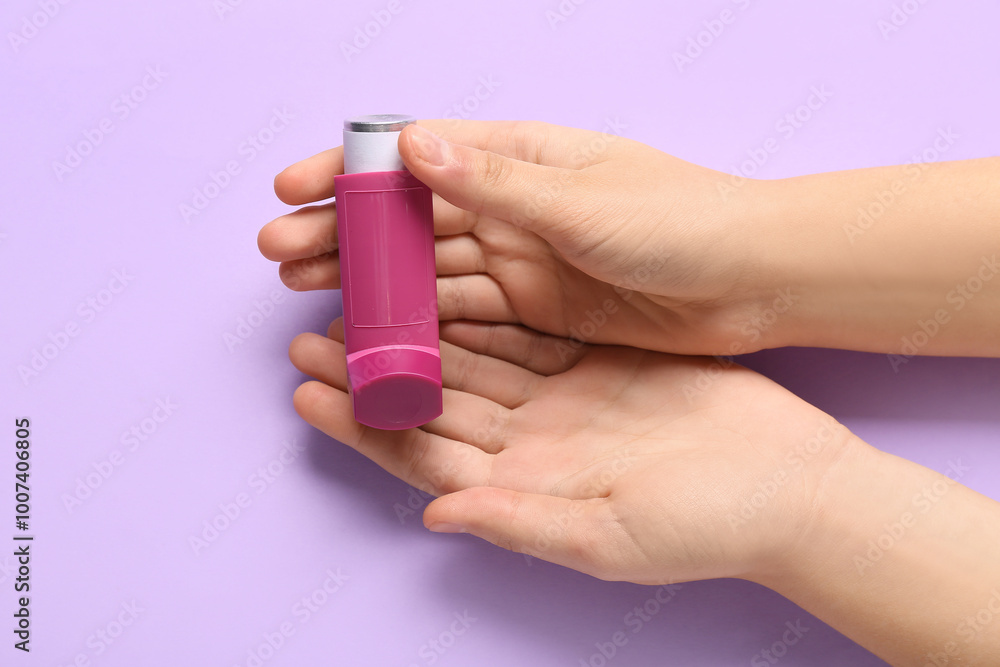 Child's hands with asthma inhaler on lilac background Child's hands with asthma inhaler on lilac background