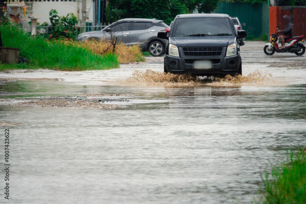 A black car is driving through a flooded street. The water is up to the car's hood A black car is driving through a flooded street. The water is up to the car's hood