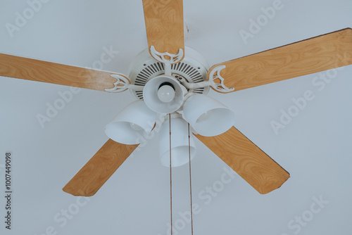 electric lamps and Ceiling fan with five wooden blades hangs from white ceiling. Copy space image photo