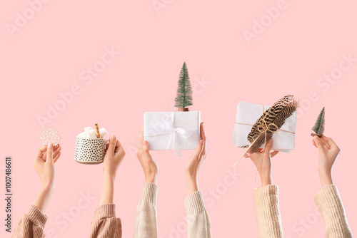 Female hands with Christmas gifts, decorations and cup of cocoa drink on pink background photo